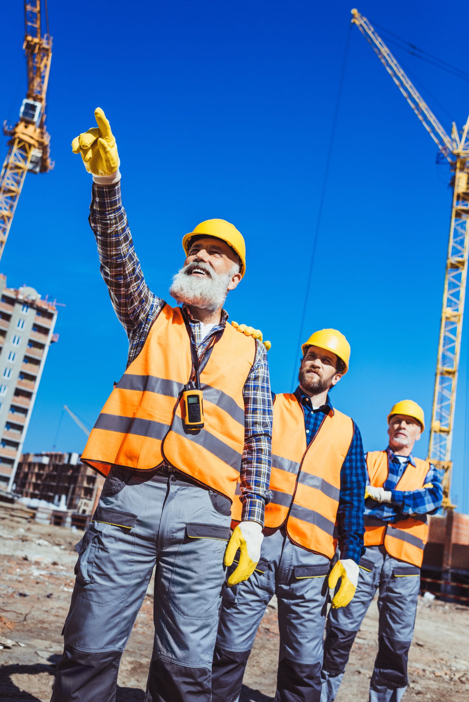 Foreman pointing his finger and showing something to other workers at construction site Foreman pointing his finger and showing something to other workers at construction site