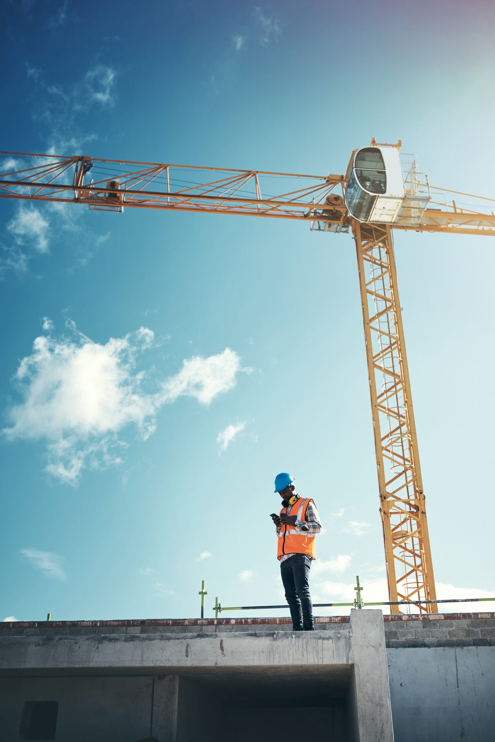 Shot of a young man using a smartphone while working at a construction site. Shot of a young man using a smartphone while working at a construction site.